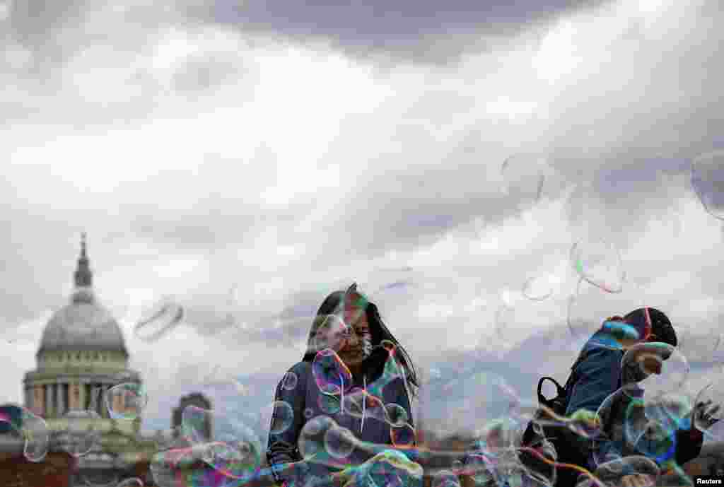 People walk through soap bubbles in front of St Paul's Cathedral in London.