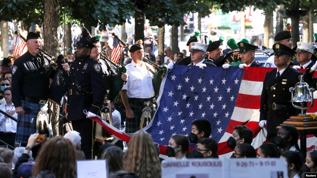 A New York police bagpipe team plays as they stand with an American flag from the World Trade Center during a ceremony marking the 20th anniversary of the September 11, 2001 attacks in New York City, Sept. 11, 2021.