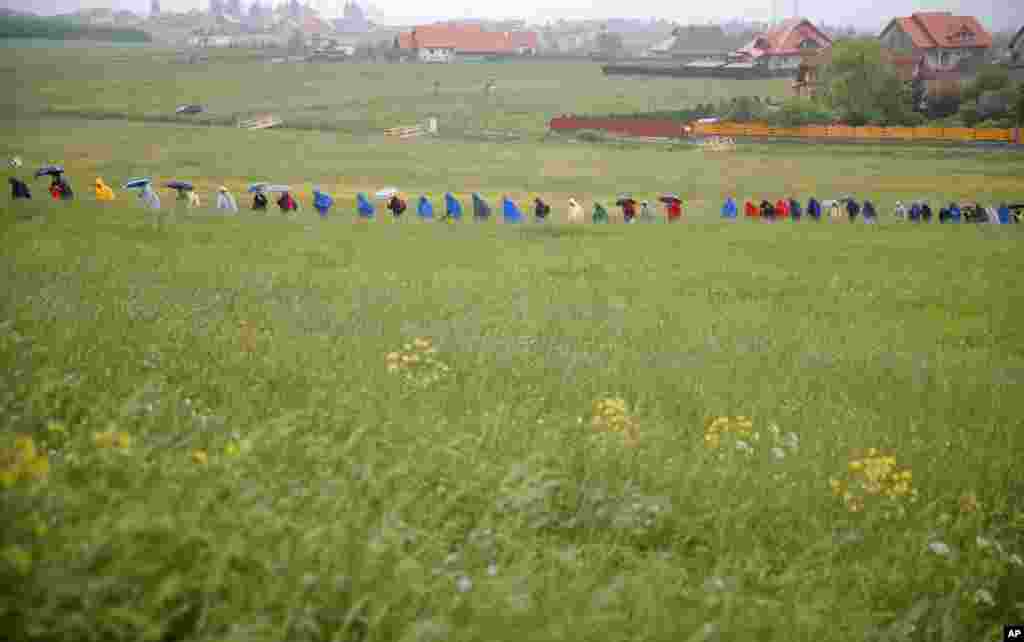 Pilgrims make their way through muddy fields during a heavy rainfall to attend Pope Francis' Mass at the Marian shrine, in Sumuleu Ciuc, Romania, June 1, 2019.