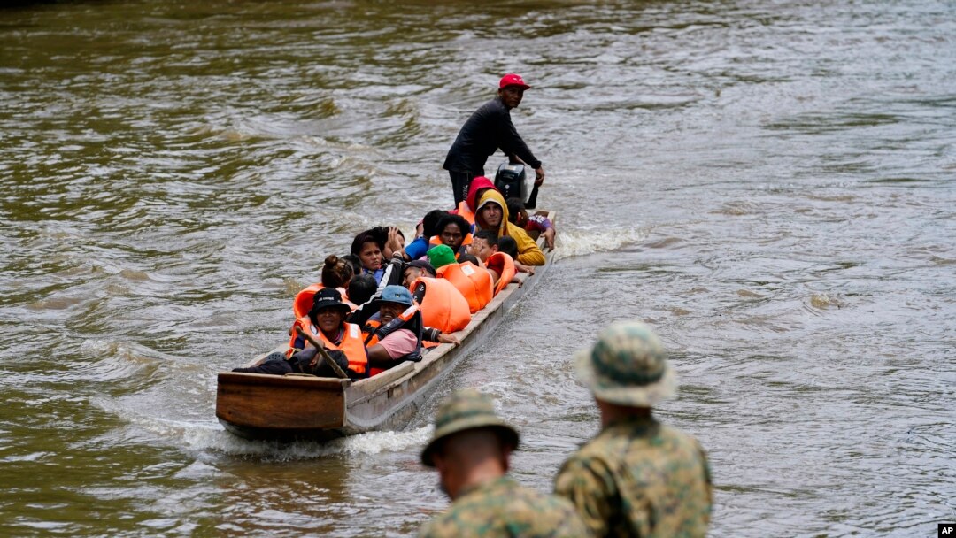 Migrantes que se dirigen al norte llegan a Lajas Blancas, donde un agente de la policía fronteriza panameña se encuentra en la orilla del río Chucunaque, en la provincia de Darién, Panamá, el 6 de octubre de 2023, después de cruzar caminando el Tapón del Darién desde Colombia.