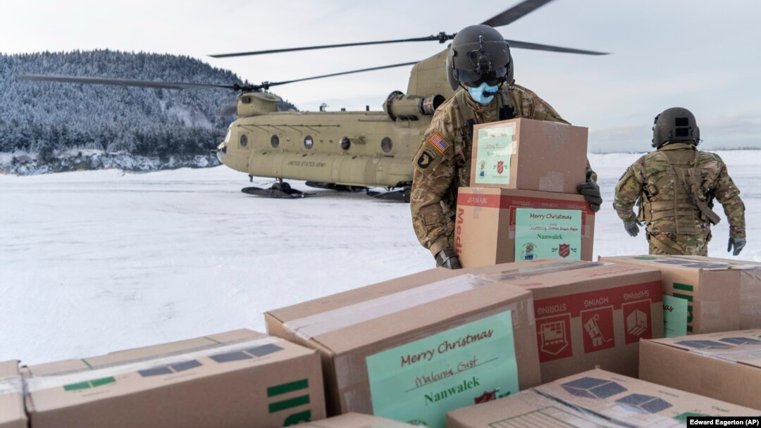 In this photo provided by the Alaska National Guard, soldiers from 1st Battalion, 207th Aviation Regiment, unload gifts from a CH-47 Chinook helicopter in Nanwalek, Alaska, during Operation Santa Claus, on Dec. 11, 2020.