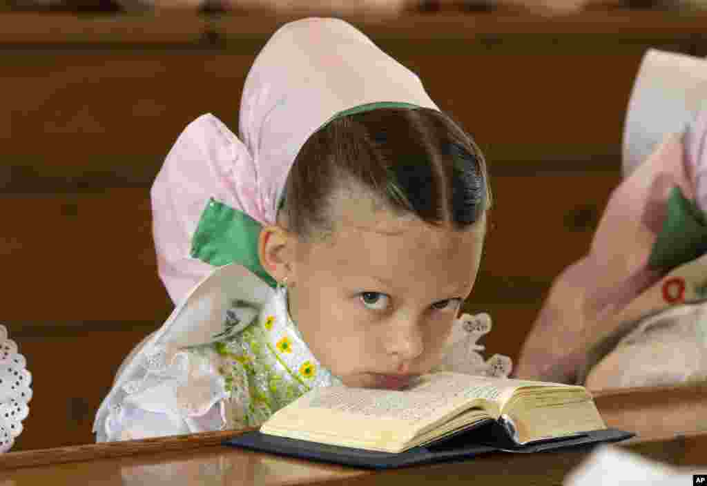 A child dressed in the traditional clothes of the Sorbs attend a holy mass during a Corpus Christi procession in Crostwitz, Germany.