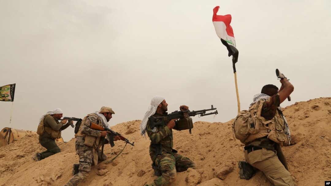 FILE - Fighters from Badr Brigades Shiite militia clash with Islamic State group militants at the front line on the outskirts of Fallujah, Anbar province, Iraq, June 1, 2015. 