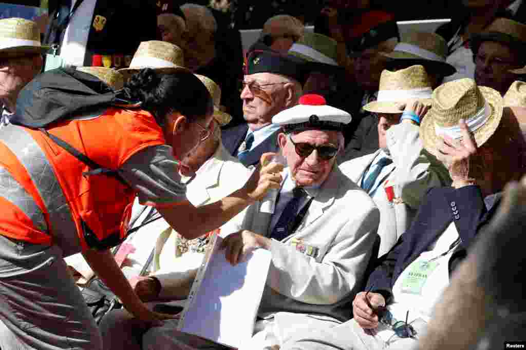 A worker of the Red Cross sprays water on a veteran during a ceremony in Boulouris, France, marking the 75th anniversary of the Allied landings in Provence in World War II which helped liberate southern France.