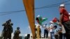 Demonstrators hold Palestinian flags in front of Israeli soldiers during a protest against the United Arab Emirates' deal with Israel to normalize relations, in Haris near Salfit in the Israeli-occupied West Bank, Aug. 14, 2020.