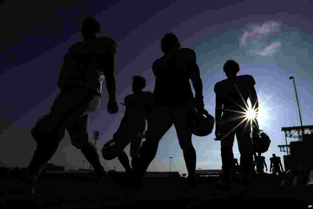 Houston Texans' players walks across a practice field before the start of a joint NFL training camp football practice with the Detroit Lions in Houston.