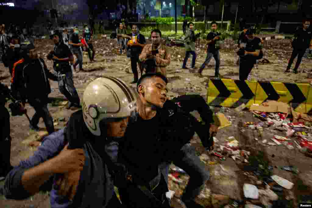 An injured police officer leaves the area with the help of his colleagues after clashes with protesters in Jakarta, Indonesia, in this photo taken by Antara Foto.
