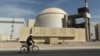 FILE: A bicyclist passes the nuclear power plant just outside Bushehr, Iran.