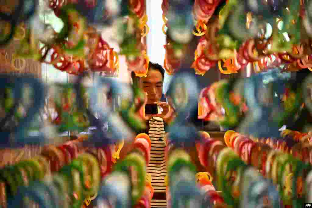 A visitor takes pictures of an art installation named '100 colors' by French architect Emmanuelle Moureaux at the Eslite bookstore in Taipei. The art installation is made of 8,000 paper-cut numbers.