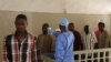 FILE - A health worker, center, takes the temperature of people to see if they might be infected by the Ebola virus inside the Ignace Deen government hospital in Conakry, Guinea, March 18, 2016.