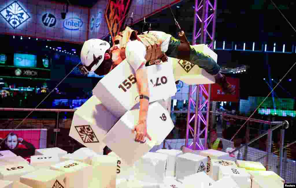 A blind-folded gamer collects as many foam cubicles as possible as he hangs from the ceiling at the first day of Europe's leading digital games fair Gamescom, which showcases the latest trends of the computer gaming scene in Cologne, Germany.