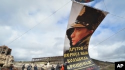 Enthusiasts fix a portrait of Russian President Vladimir Putin to a balloon during celebration of the anniversary of Crimea annexation from Ukraine in 2014, in Sevastopol, Crimea, March 18, 2021.