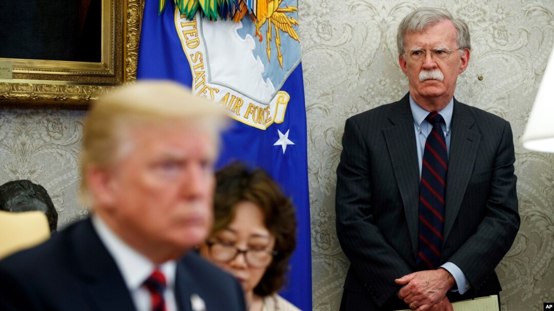 FILE - U.S. President Donald Trump, left, conducts a meeting in the Oval Office of the White House in Washington, May 22, 2018, as then-National Security Adviser John Bolton, right, looks on. 