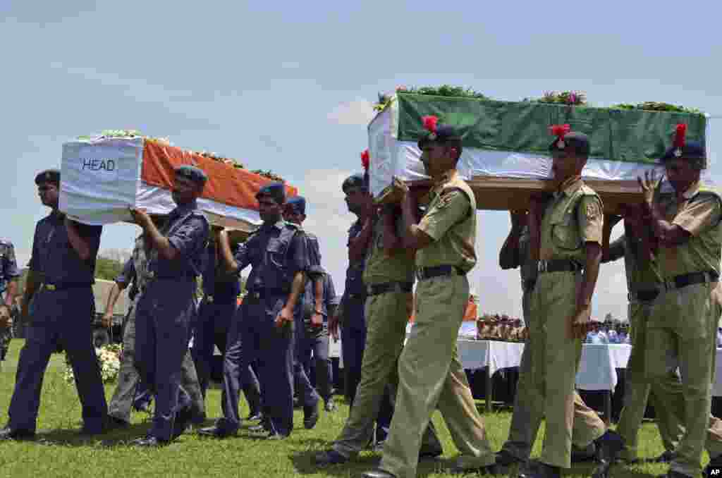 Indian security officers carry coffins containing victims of a helicopter that crashed during a rescue mission in flood-ravaged northern India, in Dehradun, India. The air force helicopter hit the side of a mountain and fell into a river on Tuesday, killing five crew members and three civilians on board.