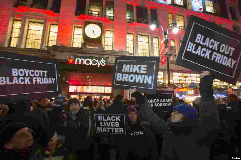 Protesters hold signs aloft outside Macy's before the kick off of Black Friday sales in New York, November 27, 2014.
