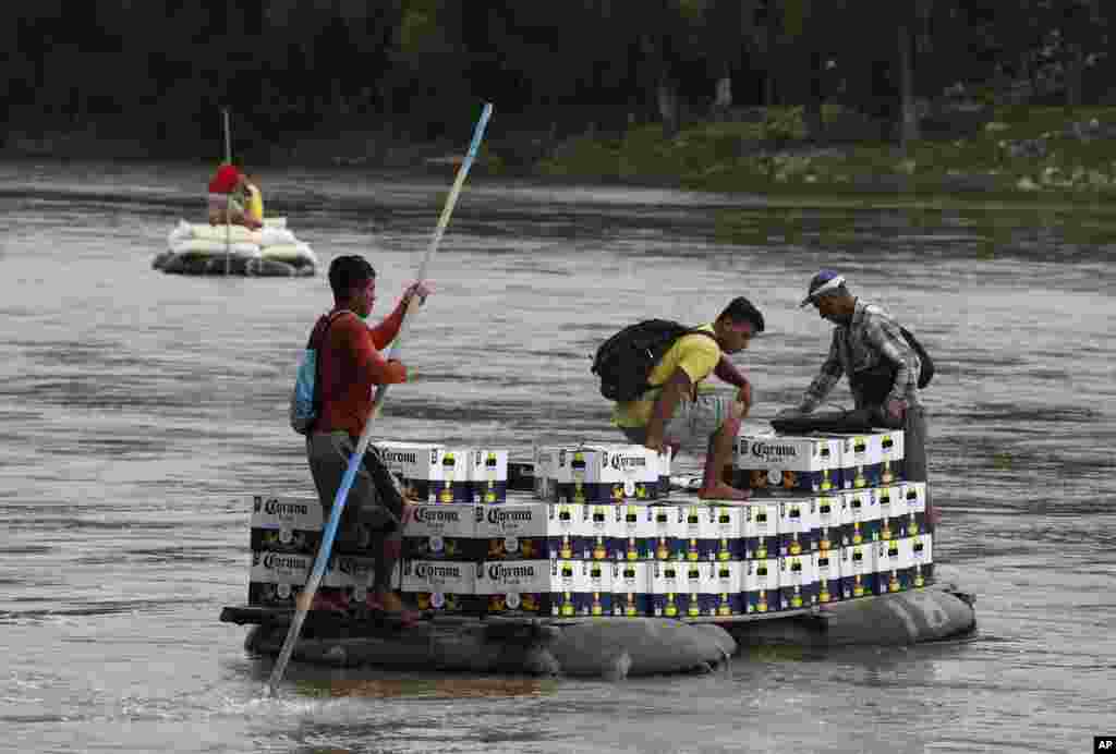 Men cross the Suchiate Rivera with a load of Corona beer on an inner tube and plank raft, near Ciudad Hidalgo, Mexico, June 17, 2019, on the border with Guatemala.