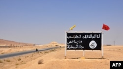 FILE - This photo taken Aug. 13, 2017, shows an Islamic State group sign in the central Syrian town of al-Sukhnah.