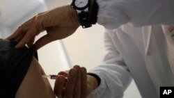 FILE - A doctor injects vaccine into a patient's arm, in Rome, Italy, Feb. 23, 2018.