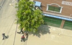 A security officer kicks a man lying on the street in Sanchaung, Yangon, Myanmar, March 27, 2021 in this still image taken from video.