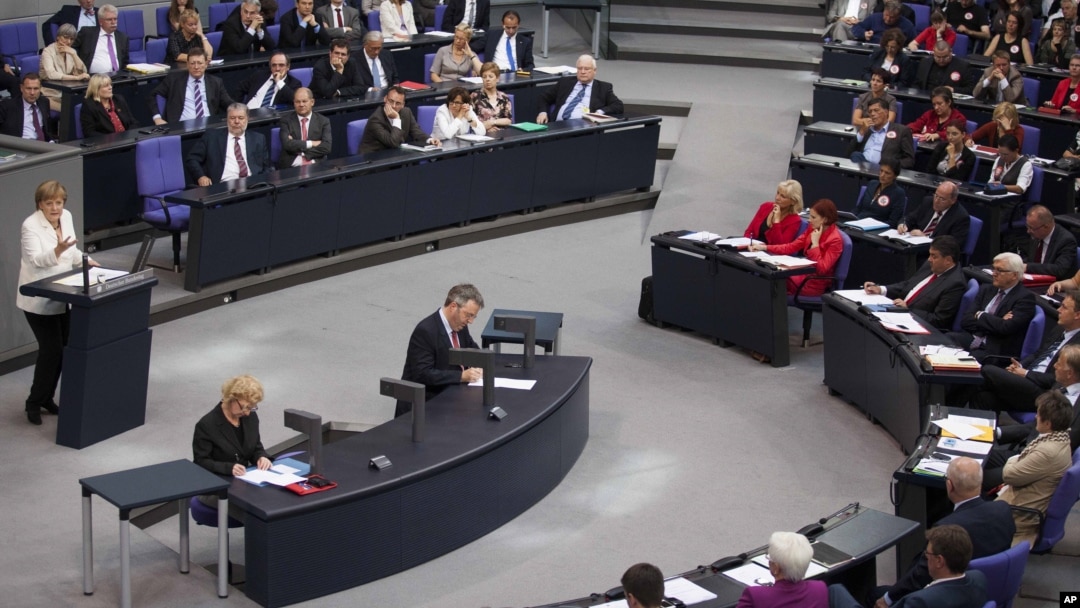 German Chancellor Angela Merkel, left, addresses lawmakers on the decisions of the EU summit at the parliament Bundestag in Berlin, June 29, 2012.