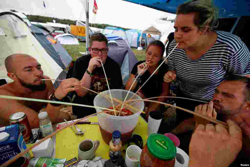 Festival goers from the north-eastern German city of Greifswald use straws to drink from a self-mixed brew of fruits, juice, wine and booze during drinking games at a camp site for the world's largest heavy metal festival, the Wacken Open Air 2019, in Wacken, Germany.