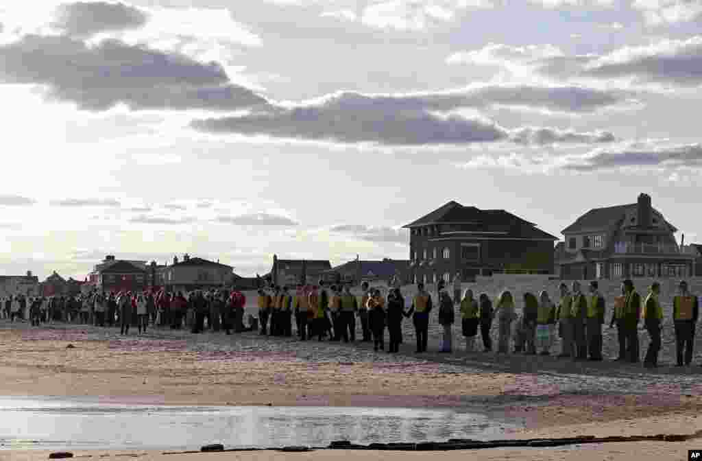 People line up along the beach in Belle Harbor during the "Rockaway Rising: Hands Across the Sand," commemoratation of the one year anniversary of Superstorm Sandy, Oct. 27, 2013, in New York.