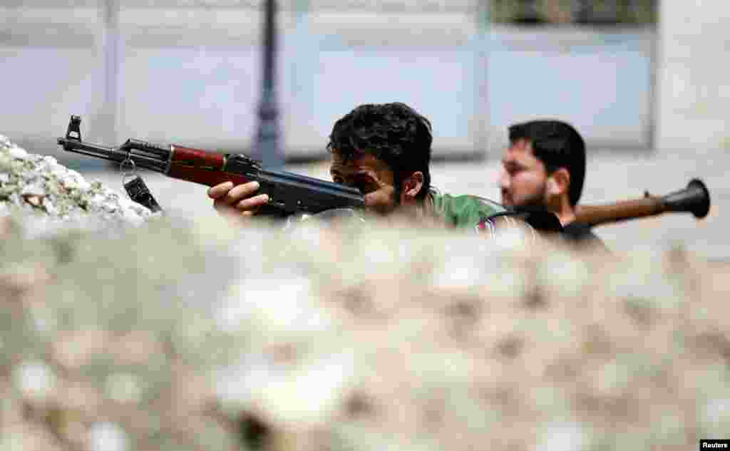 Free Syrian Army fighters sit behind a barricade on a street in Aleppo, August 13, 2012.