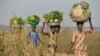 FILE - Women come back from the fields to sell vegetables at a market near the displacement camp close to the airport in Bangui.