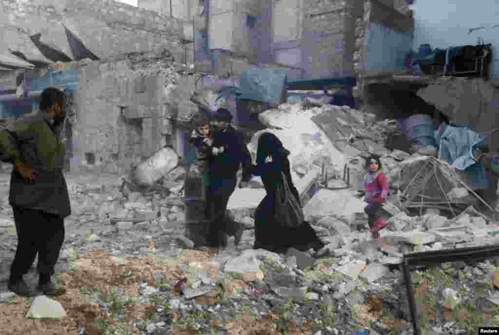 People walk on rubble of collapsed buildings at a site hit by what activists said were barrel bombs dropped by government forces in Aleppo, Syria, Jan. 29, 2014. 