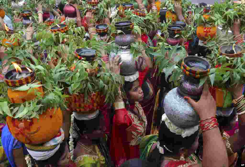 Indian women carry pots filled with cooked rice decorated with turmeric and neem leaves on their heads during the 'Bonalu' festival in Hyderabad, India. Bonalu is a month-long Hindu folk festival of the Telangana region dedicated to Kali, the Hindu goddess of destruction.