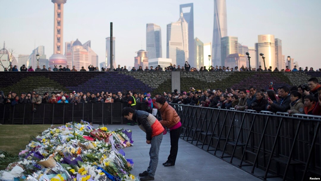 People bow during a memorial ceremony for people who were killed in a stampede incident during a New Year's celebration on the Bund, in Shanghai, Jan. 2, 2015.