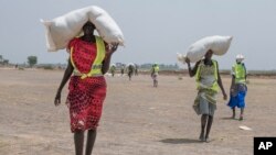 Women walk back to their homes after receiving food distributed by ICRC at a site in Leer County region of South Sudan, Tuesday, April 11, 2017.