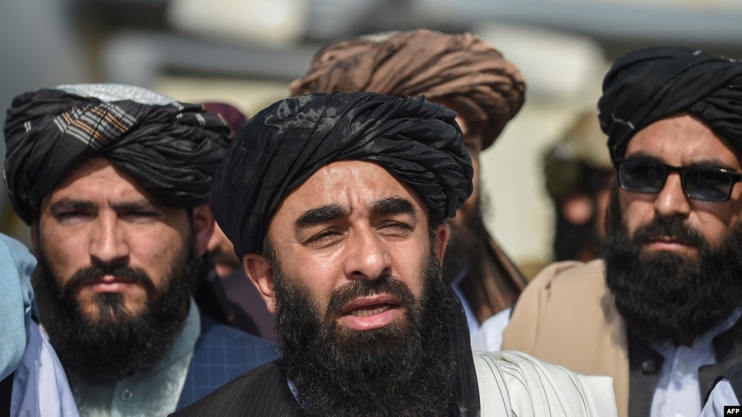 Taliban spokesman Zabihullah Mujahid, center, addresses a media conference at the airport in Kabul on Aug. 31, 2021.