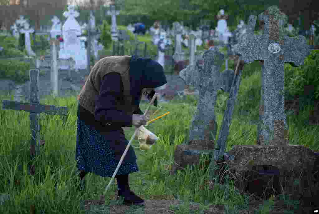 An elderly woman walks to a relative's grave at dawn in Copaciu, Romania.