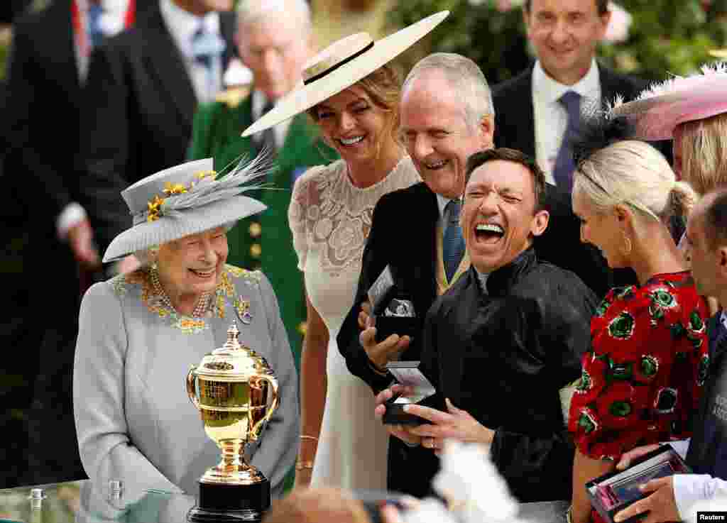 Britain's Queen Elizabeth II (L) watches as Italian jockey Frankie Dettori (R) celebrates with the trophy after he won the Gold Cup on horse Stradivarius, his fourth win of the day, on day three of the Royal Ascot horse racing meet, in Ascot, west of London.